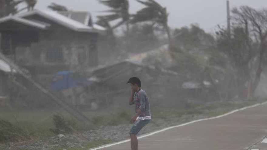 Un joven resiste la fuerza del viento, ayer en Baggao, Filipinas. // Efe