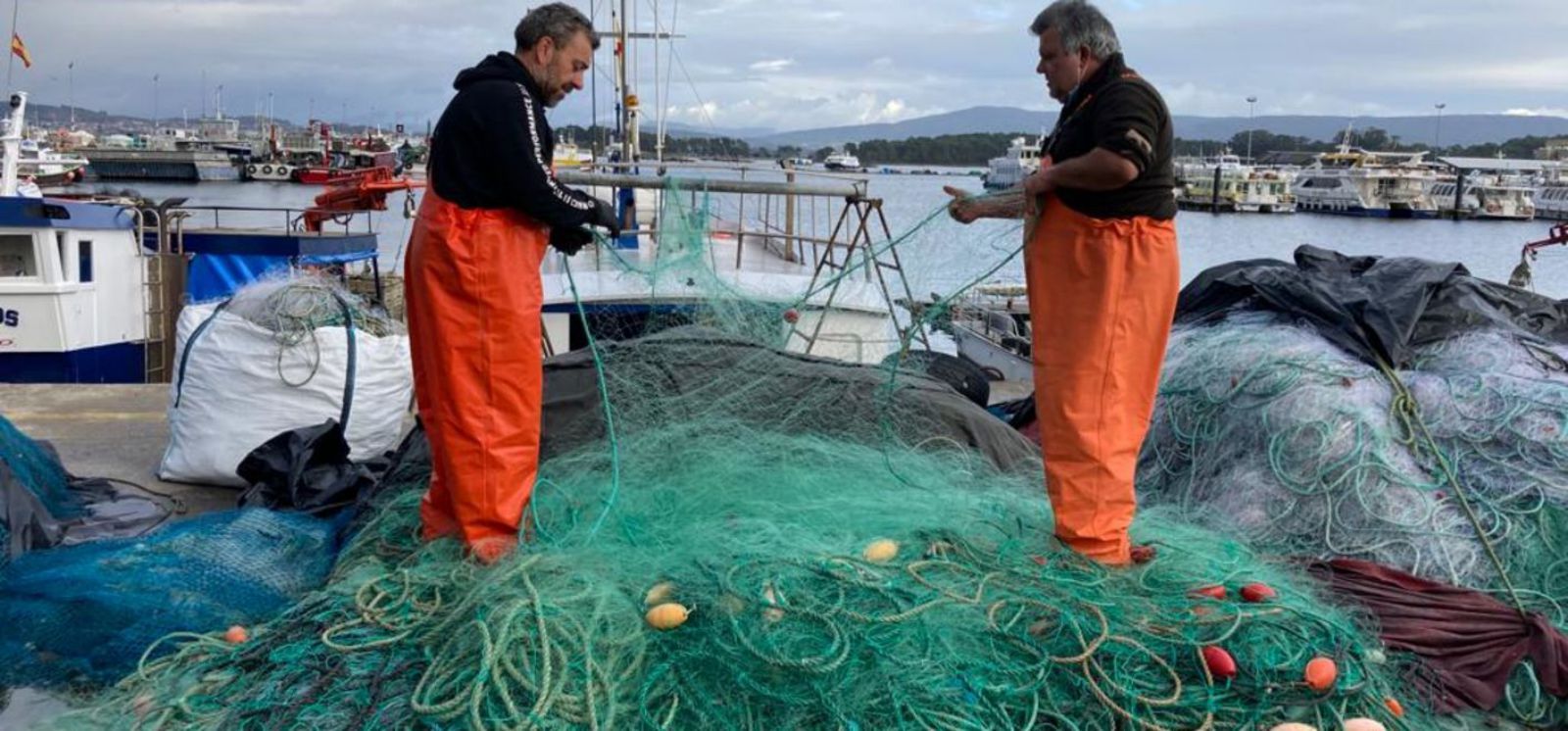 Dos marineros retiran las “volantillas” de su barco (ayer) para empezar hoy a cargar los “miños” a bordo. 