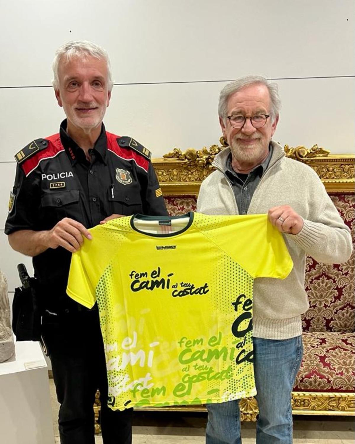 Steven Spielberg amb la samarreta de la caminada solidària acompanyat d'un agent