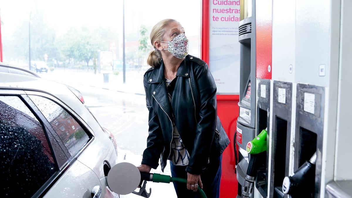 Una mujer reposta gasolina en una estación de servicio.