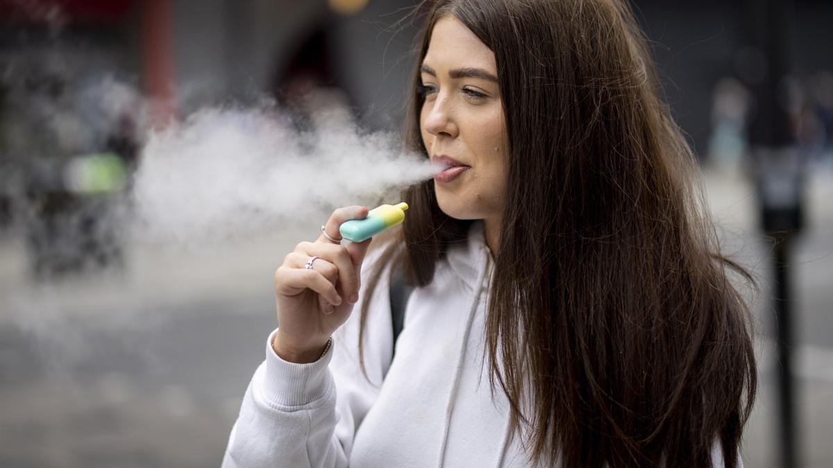 Una joven fuma con su cigarrillo electrónico.
