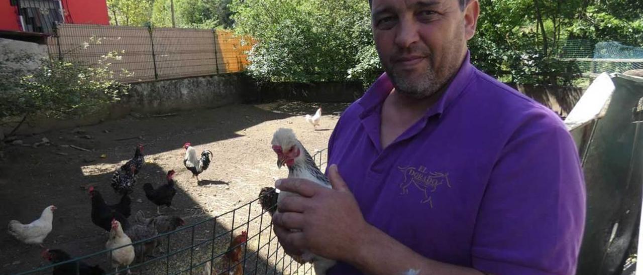 Fernando Villarroel, con sus aves en su gallinero de Sotu; al fondo, de rojo, el hotel rural.