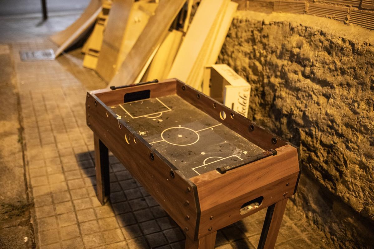 Un futbolín antiguo y restos de muebles de madera, en una calle de Sant Andreu.