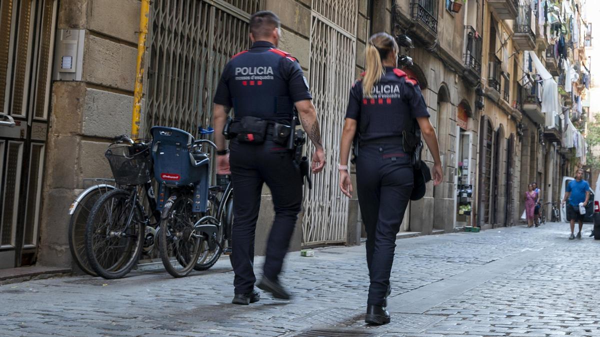 Miembros del cuerpo de los mossos d’esquadra caminan por la calle la Paloma en el barrio del Raval.