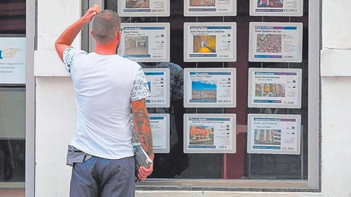 Un hombre mira el escaparate de una agencia inmobiliaria.
