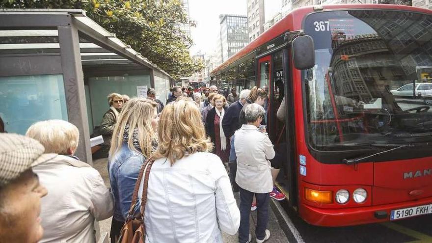 Un amplio grupo de viajeros se dispone a subir a un autobús en la plaza de Pontevedra.