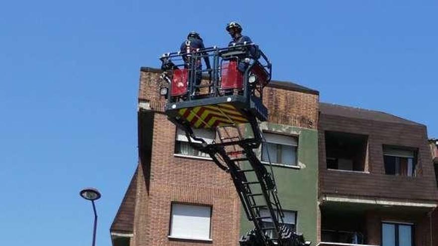 Bomberos de Gijón, subidos a una grúa para asegurar el edificio.