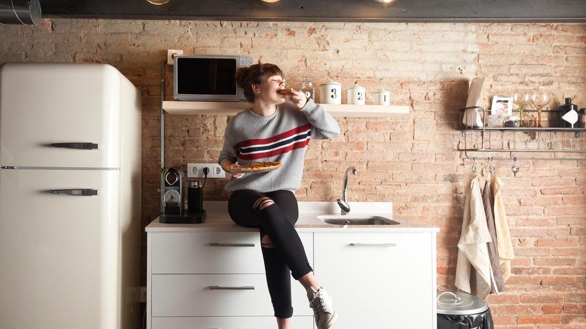 Mujer en la cocina con electrodomésticos nevera microondas, lavadero decoración