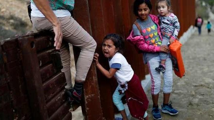 Una niña llora al pasar la valla en Tijuana ( México). // Reuters