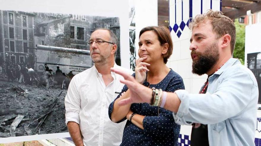 Álex Zapico explica una fotografía de la exposición a Carmen Moriyón en presencia de Rubén Vega.