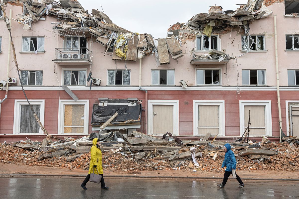 Dos personas caminan frente a un edificio bombardeado en Chernígov.