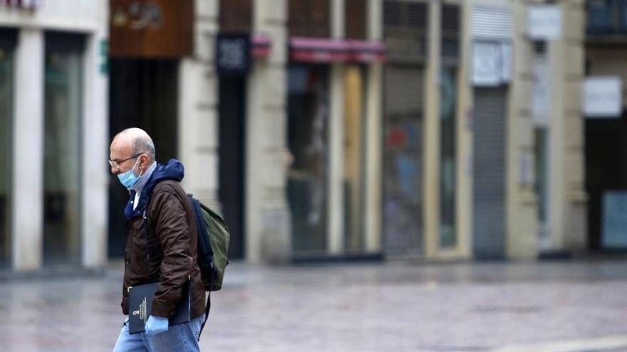Una persona camina por las calles vacías de Málaga, con todo cerrado.