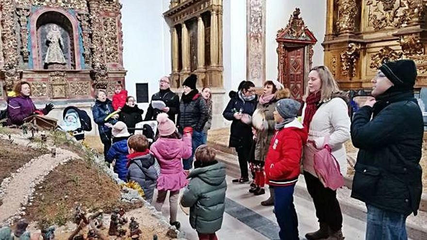 Niños y mayores entonan un villancico en la iglesia de la Concepción mientras admiran el belén municipal.