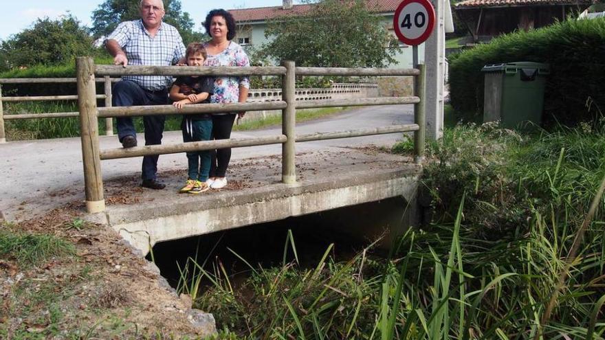 Ricardo Junquera, Covadonga Pérez y su nieto Pablo Amieva, ayer, en el puente sobre el río que da acceso a su casa, en Ferrera.