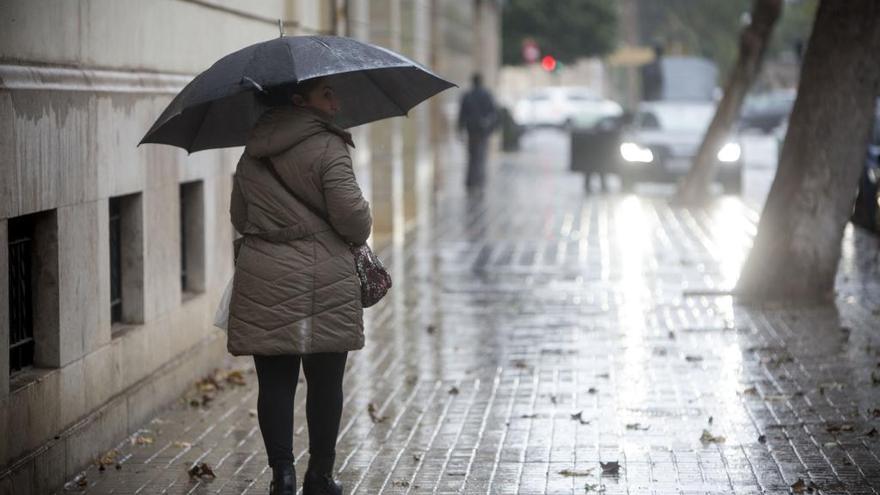Una mujer se cobija bajo un paraguas en Valencia.