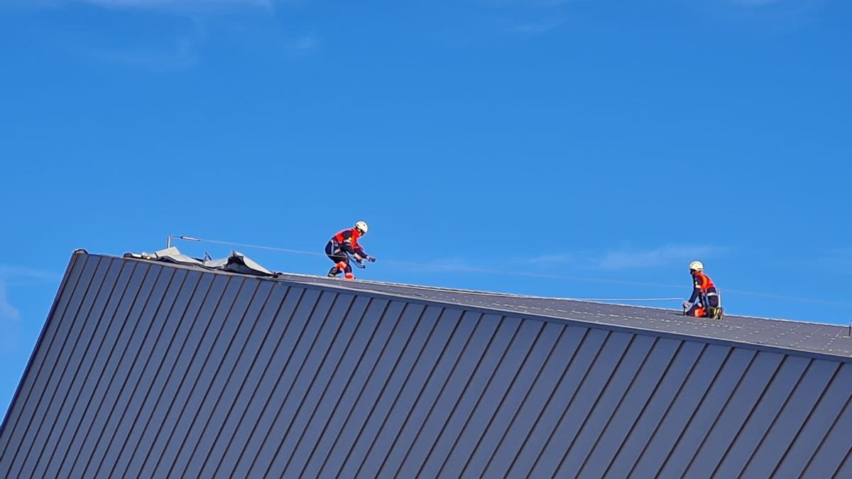 Los bomberos, durante la revisión del tejado del polideportivo.