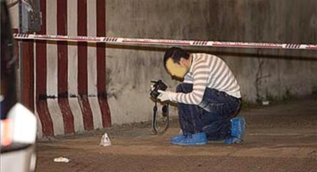 Un mosso de la policia científica fotografia una empremta en l’accés al pàrquing del carrer d’Aragó per on van fugir els atracadors.