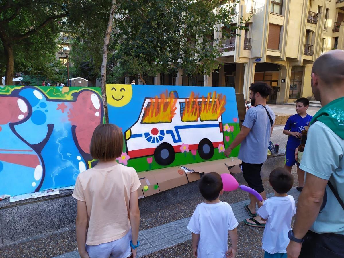 Un grupo de adultos muestra a unos niños en San Sebastián un mural que bromea con el intento de asesinato de unos ertzainas que sufrieron graves quemaduras en Rentería.