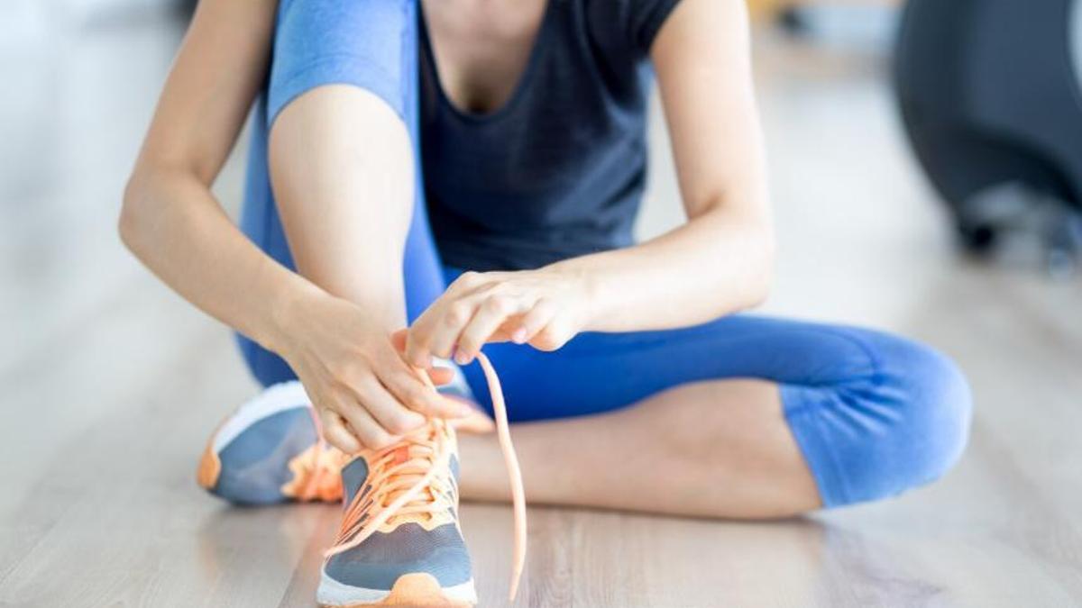 Una joven se ata los cordones de sus zapatillas de deporte