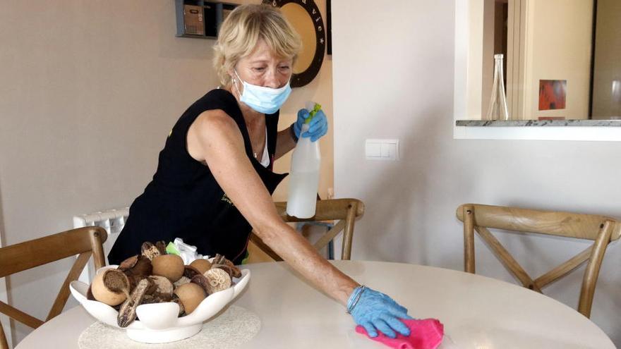 Una treballadora neteja la taula del menjador d&#039;un apartament turístic