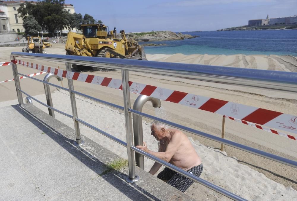 Las máquinas extienden la arena en la playa de Riazor.