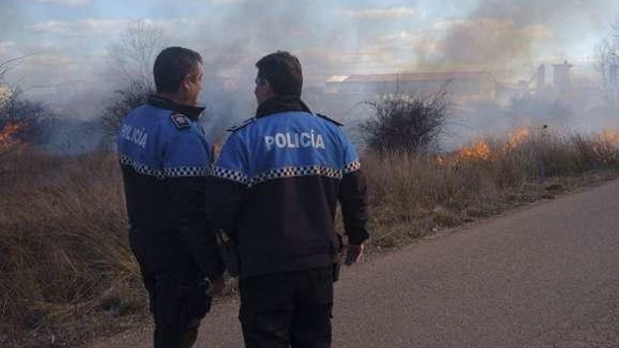 Dos agentes de la Policía Local vigilando el avance de un incendio.