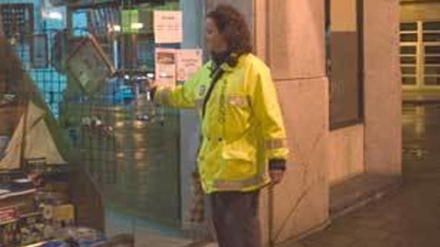 Imagen de un sereno comprobando la puerta de un comercio en Gijón.