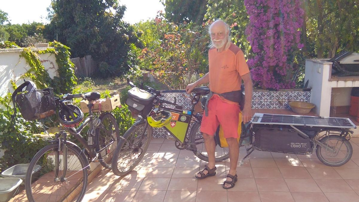 Kurt Zaugg, junto a su bicicleta y el remolque que transporta un panel solar para alimentar la batería.