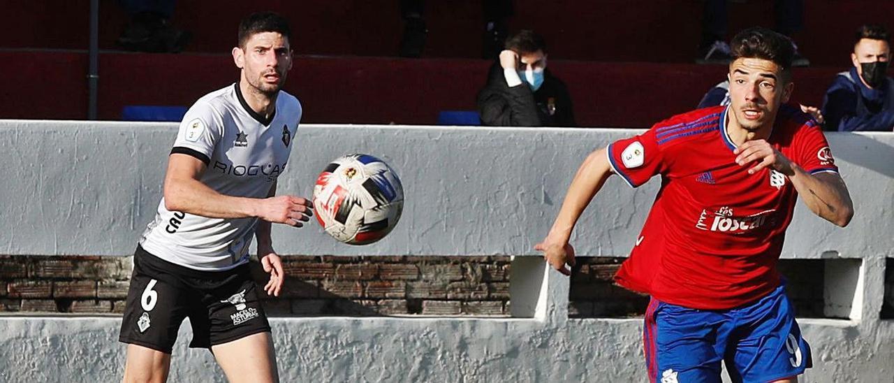 Mendi, del Caudal, al fondo, mira el balón ante la carrera del jugador del Praviano Marco Correa