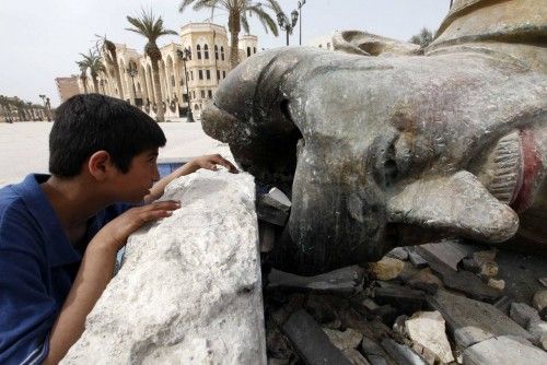 Un chico mira dentro de la estatua de Hafez Al-Assad, padre del presidente Bashar Al-Assad