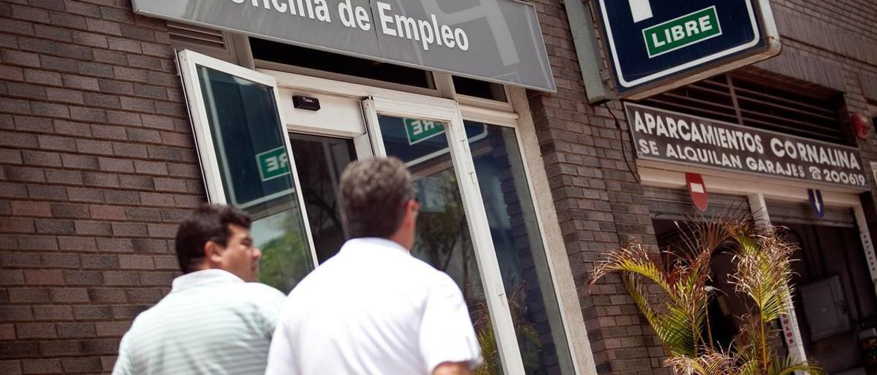 Dos hombres pasan frente a una oficina pública de empleo.