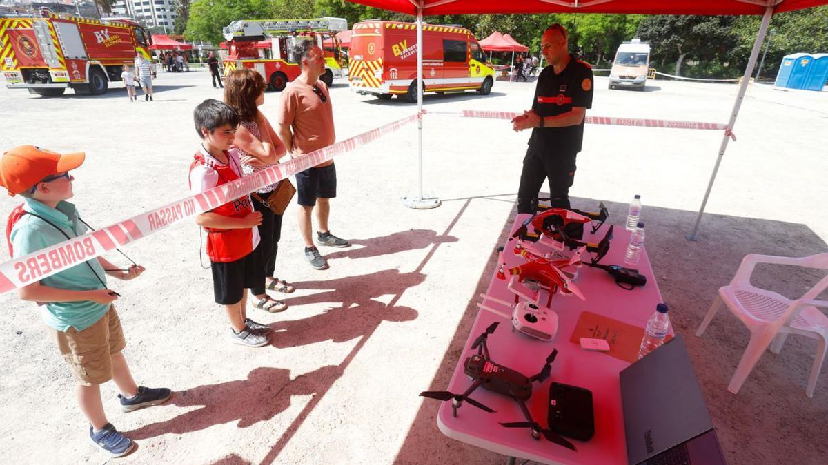 Dos niños se prueban un traje de bomberos y juegan con las mangueras para apagar incendios. | EDUARDO RIPOLL