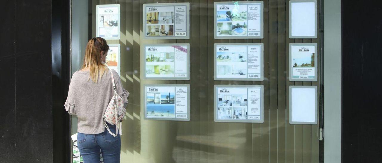 Una mujer mira las ofertas de una inmobiliaria en Alicante.