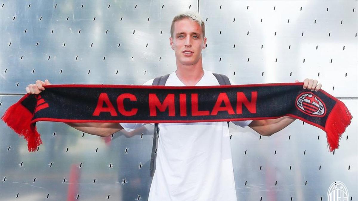 Conti exhibe la bufanda del Milan a su llegada a Milanello