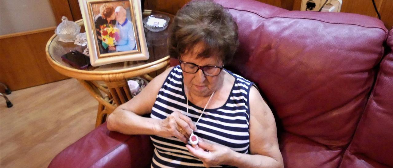 L’usuària Teresa Pascual del Río, a casa seva, observant el penjoll-botó que per a ella «és una joia»