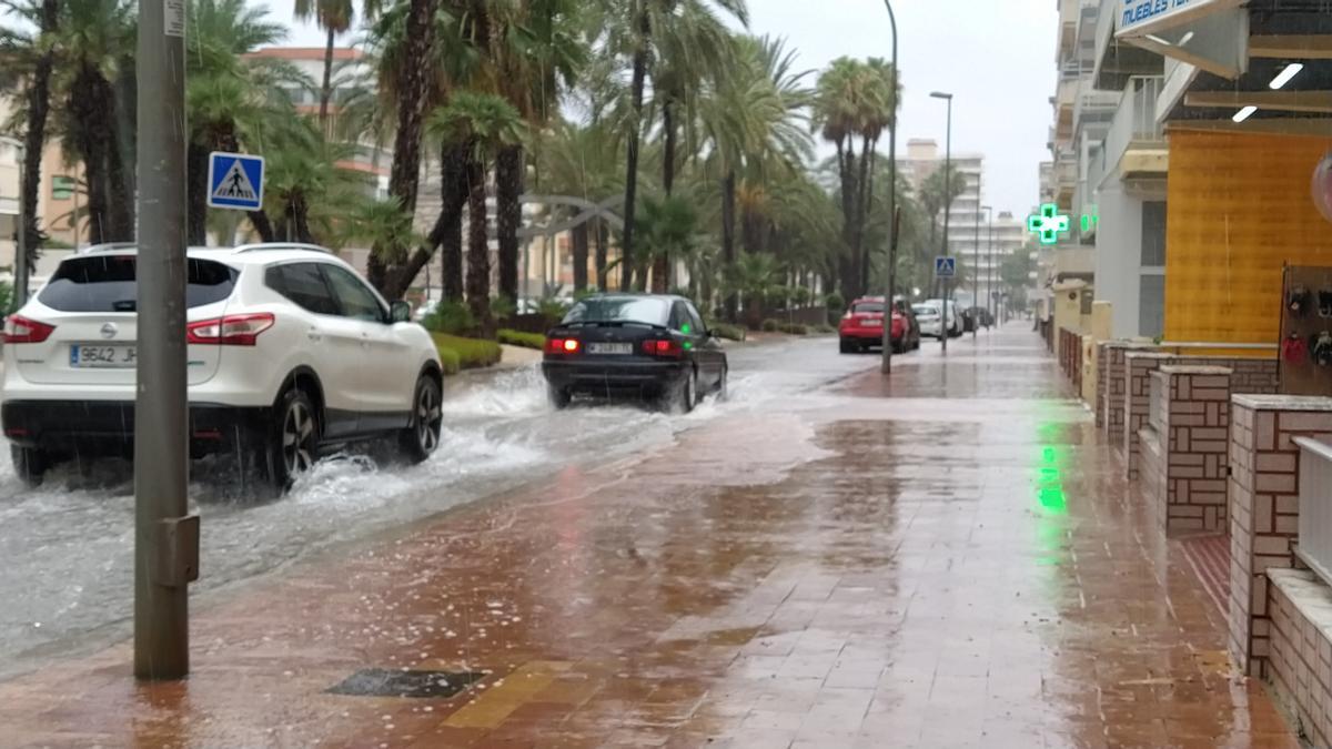 Dos coches circulan por la avenida de la Marina de Tavernes anegada