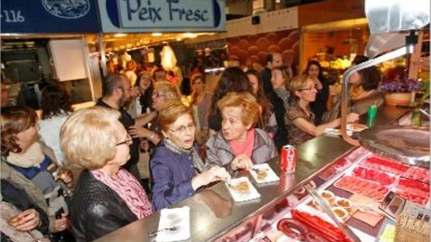 Clientes agafant alguns tastets d&#039;una parada del Mercat, durant la &quot;shopping night&quot; de Temps de Flors.