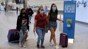 Tres jóvenes procedentes de Madrid llegan al aeropuerto de Heathrow, este domingo.