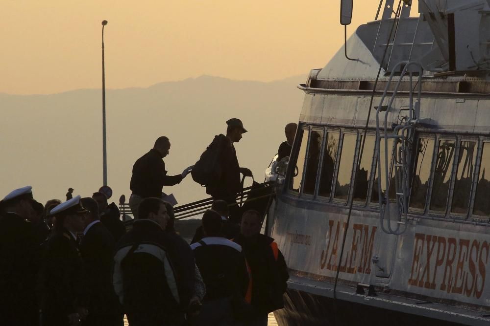 Refugiados son escoltados a un ferri en el puerto de Mytilene en la isla de Lesbos en Grecia