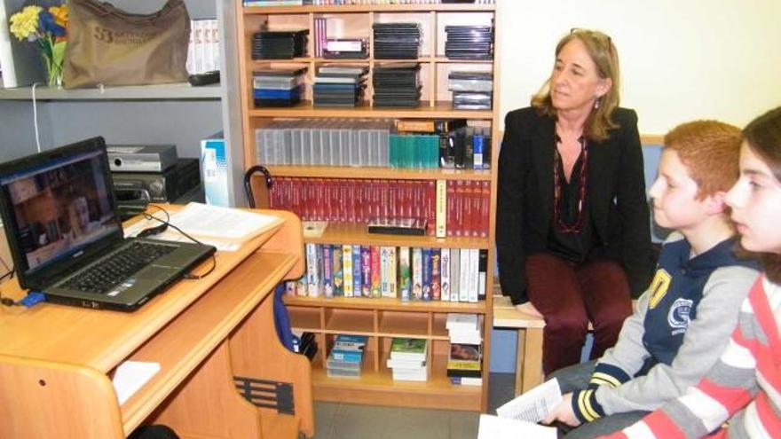 Mercedes Velasco, con dos alumnos, siguiendo la videoconferencia de Margarita Salas, en Posada.