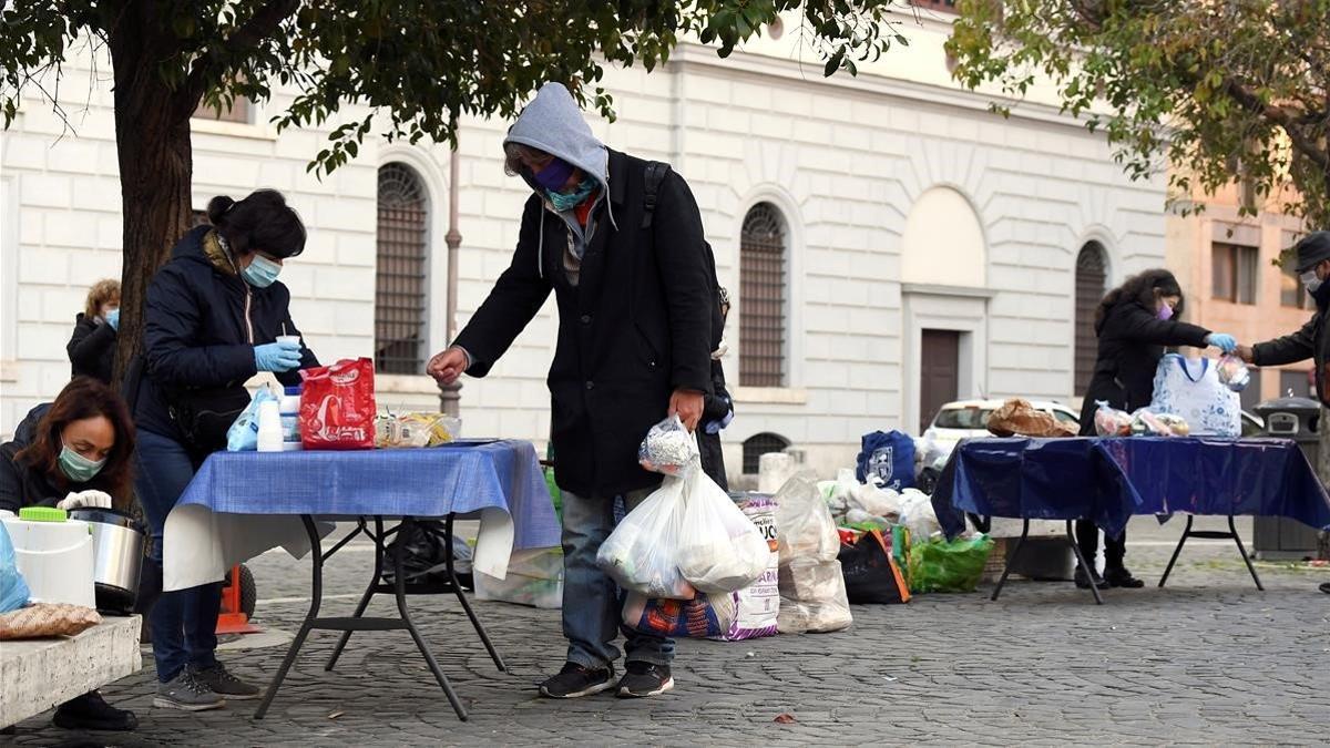 Una voluntaria ofrece desayuno gratuito a un hombre en el barrio del Trastevere de Roma, este jueves.