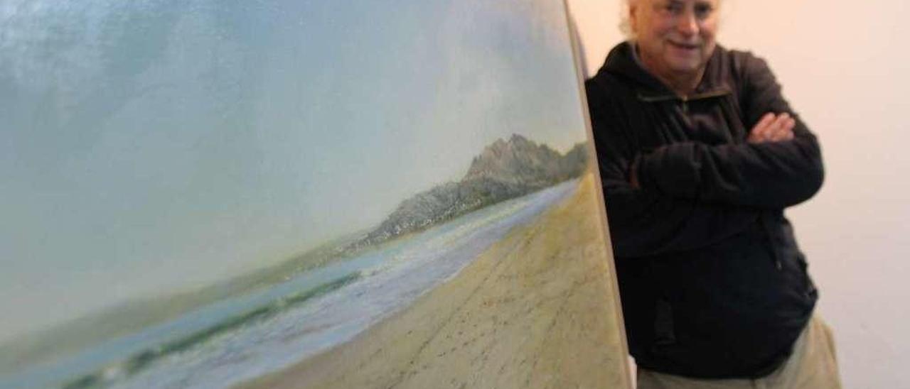 Juan Moreno Badía, ayer en la Casa de Cultura moscona, con una de las pinturas de la exposición, que refleja la playa de Carnota de La Coruña.