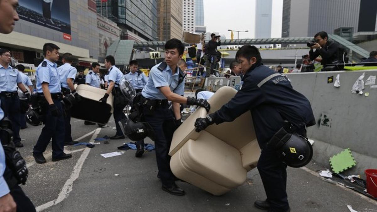 Police remove a sofa as they clear an area, previously blocked by pro-democracy supporters, near the government headquarters building at the financial Central district in Hong Kong