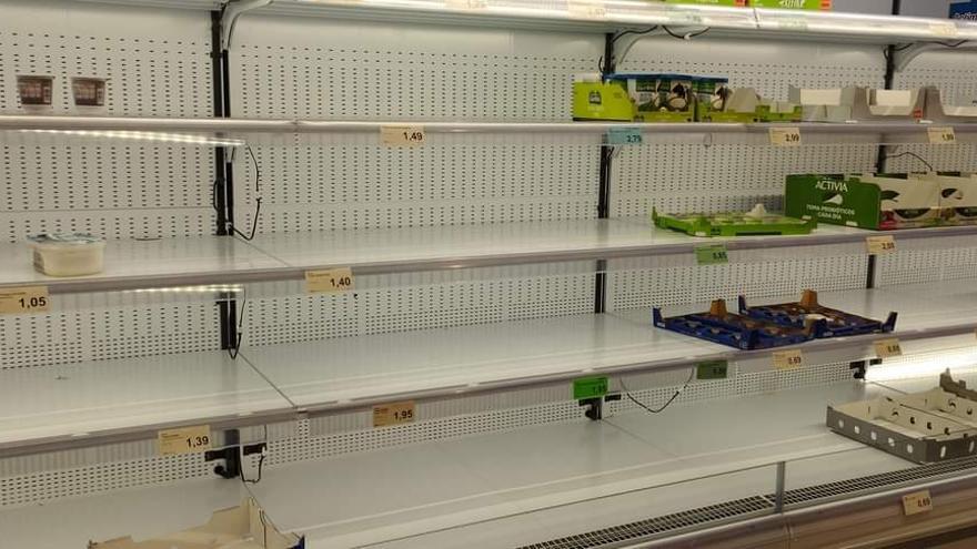 Varios estantes casi vacíos de un supermercado.