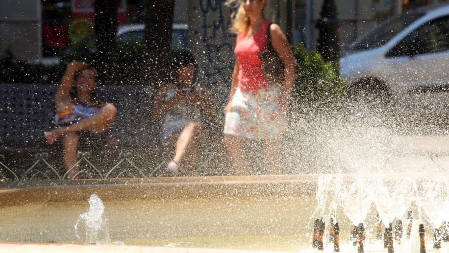 Una mujer pasea delante de una fuente en Alzira.