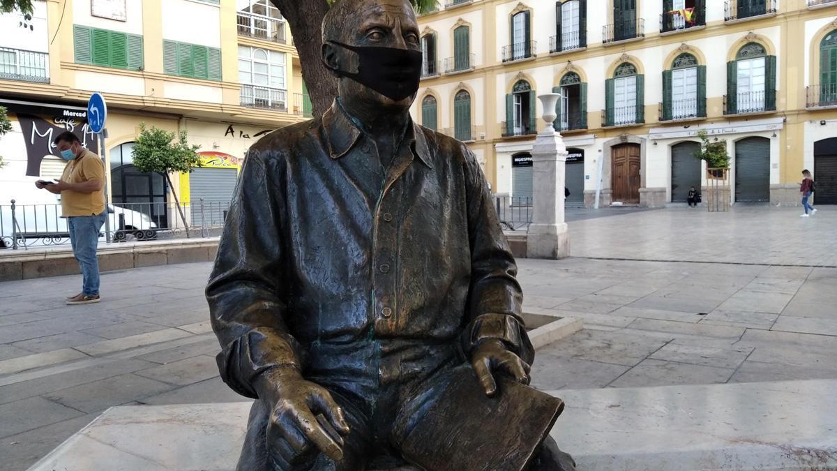 Ni las esculturas deben bajar la guardia, parece advertirnos la estatua sedente de Pablo Ruiz Picasso en un banco de la plaza de la Merced. Durante unos días de este octubre picassiano que se nos marcha el homenaje en bronce al pintor malagueño lució este aspecto, con la mascarilla de rigor. Toda precaución es poca, genios incluidos.