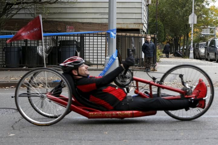 Boy watches as a man taking part in the wheelchair division makes his way up Bedford Avenue in the Williamsburg section of the Brooklyn borough during the 2015 New York City Marathon in New York