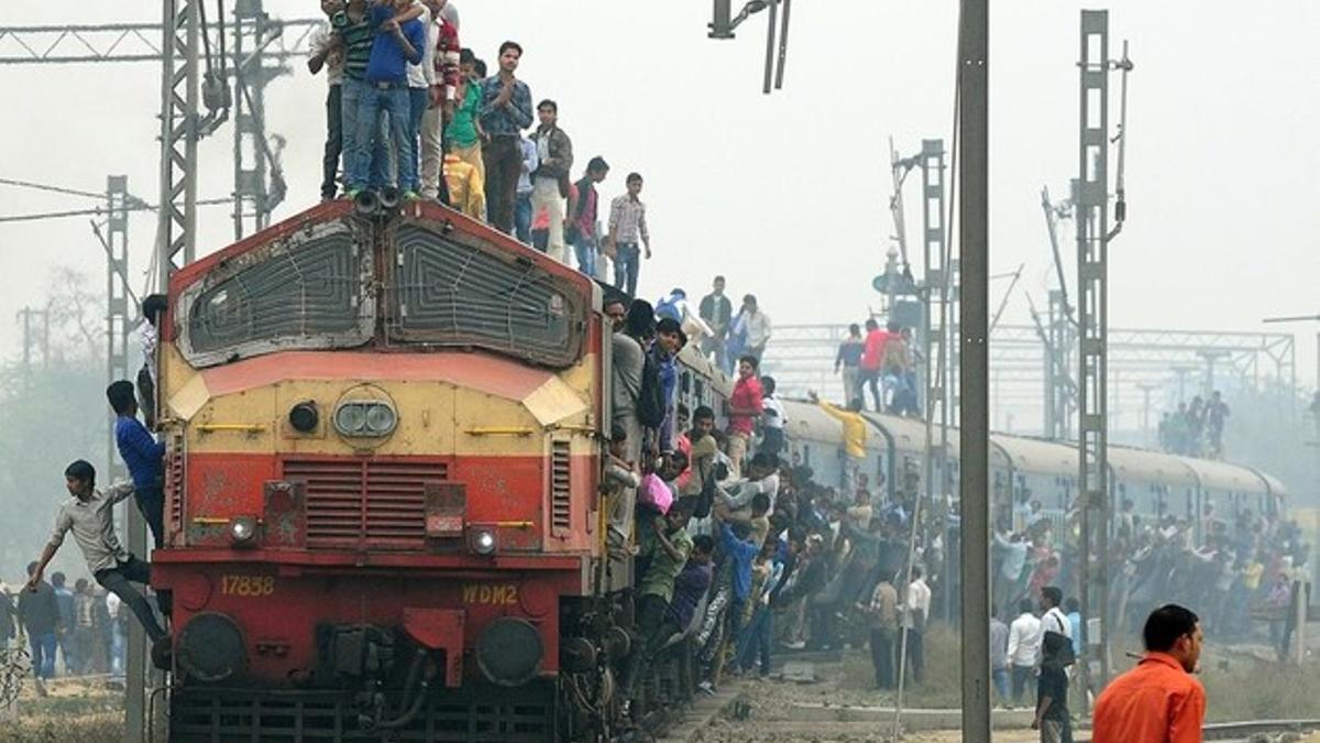 Pasajeros colgados de un tren en las afueras de Nueva Delhi, India