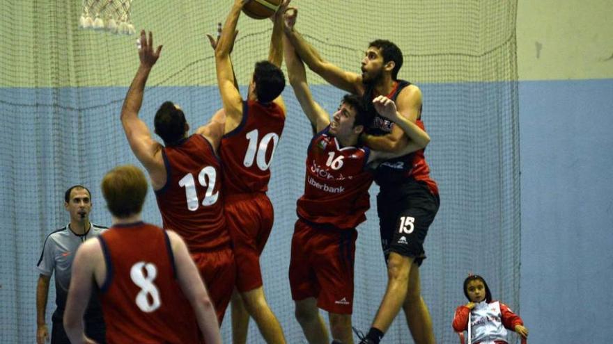 Varios jugadores luchan debajo de canasta por el balón.