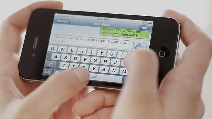 Un hombre escibe en un smartphone.